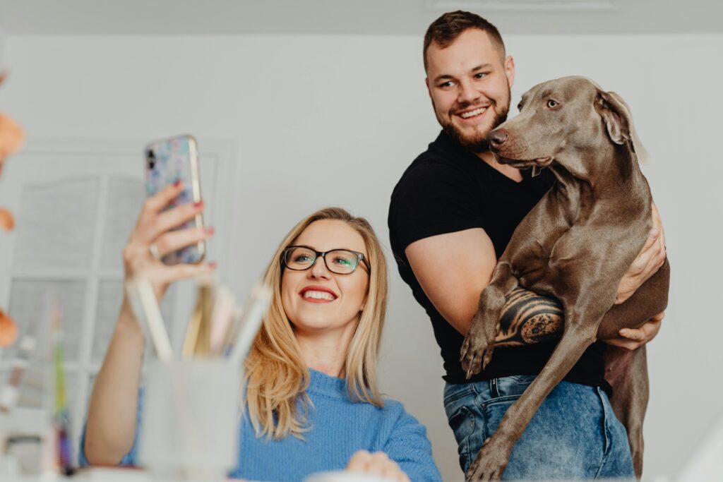 pexels photo 5908726 5908726 A cheerful couple taking a selfie with their Weimaraner dog indoors, capturing a joyful moment together.